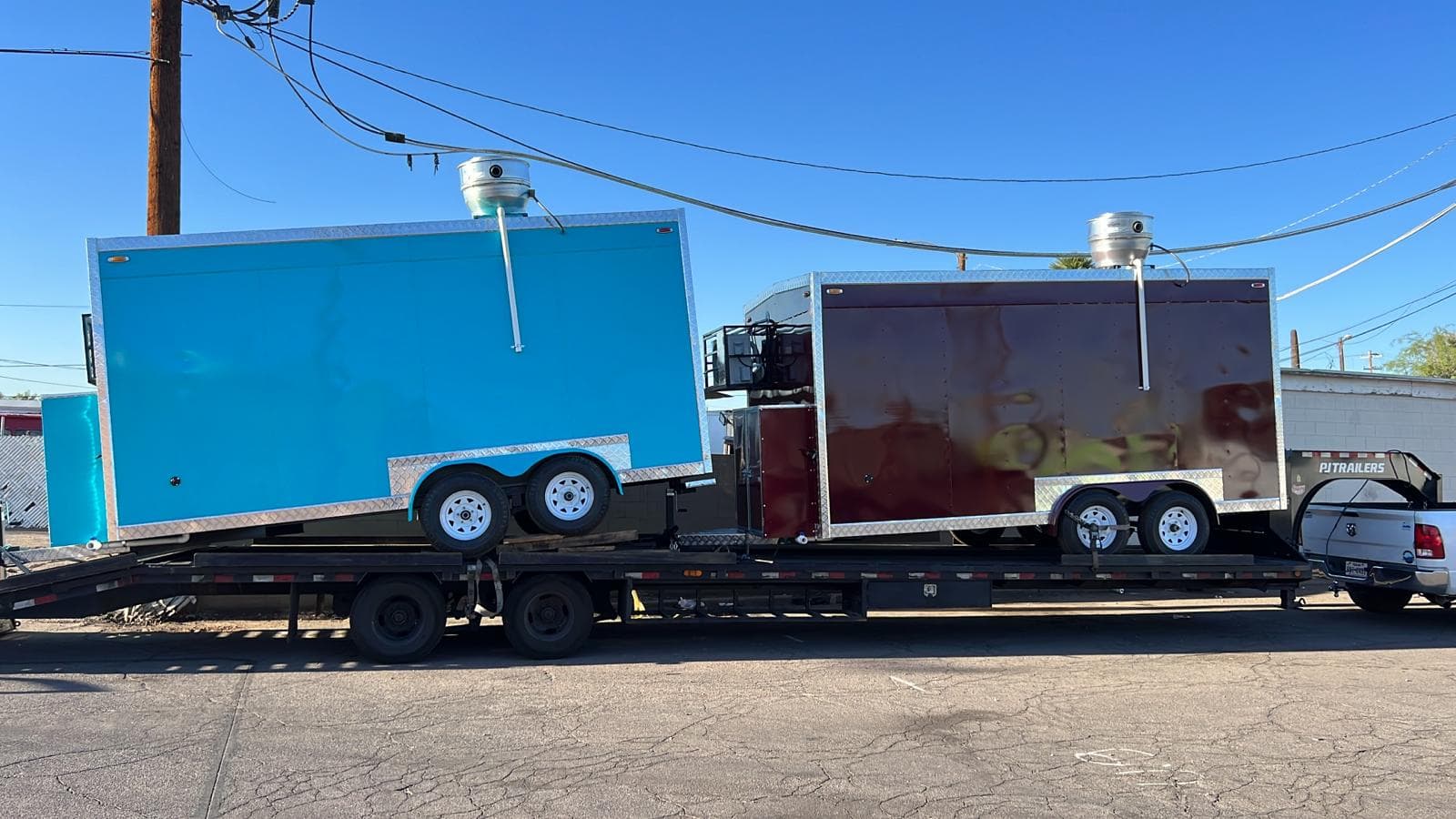 Two completed custom food trailers loaded on a transport flatbed for delivery