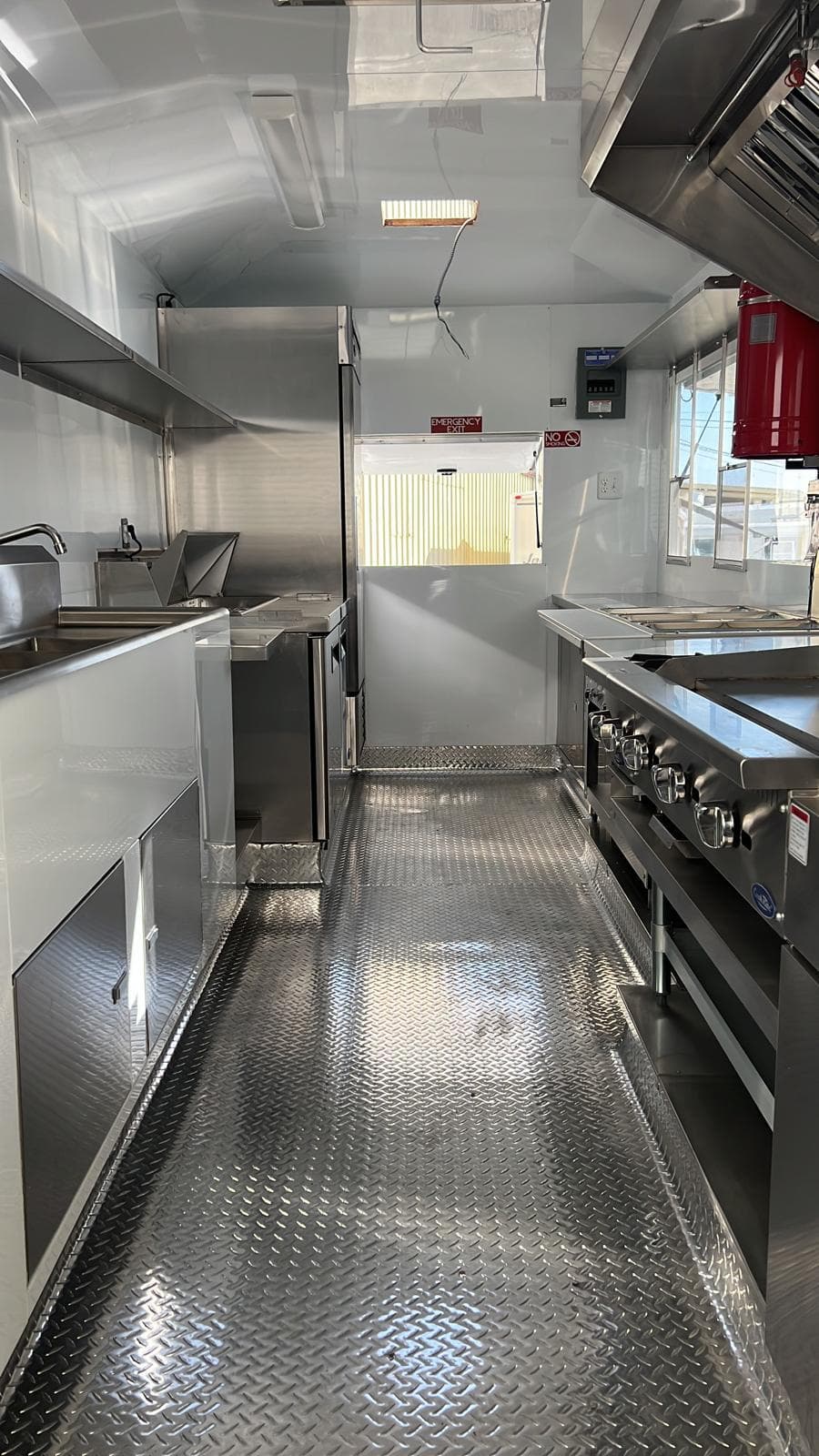 Stainless commercial kitchen interior of a custom food trailer, looking down the aisle