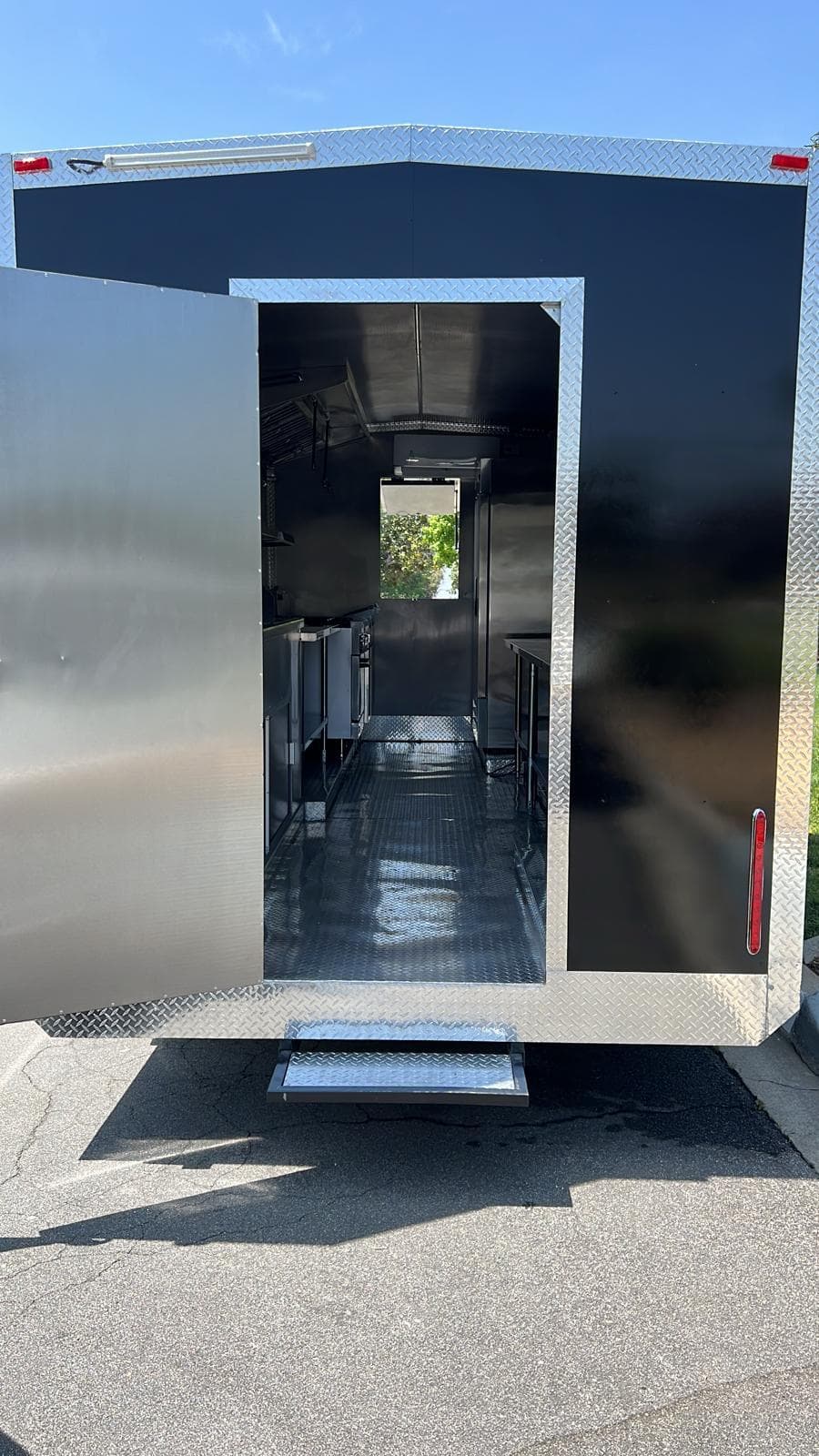 Rear entry doors open on a finished food trailer, stainless interior visible